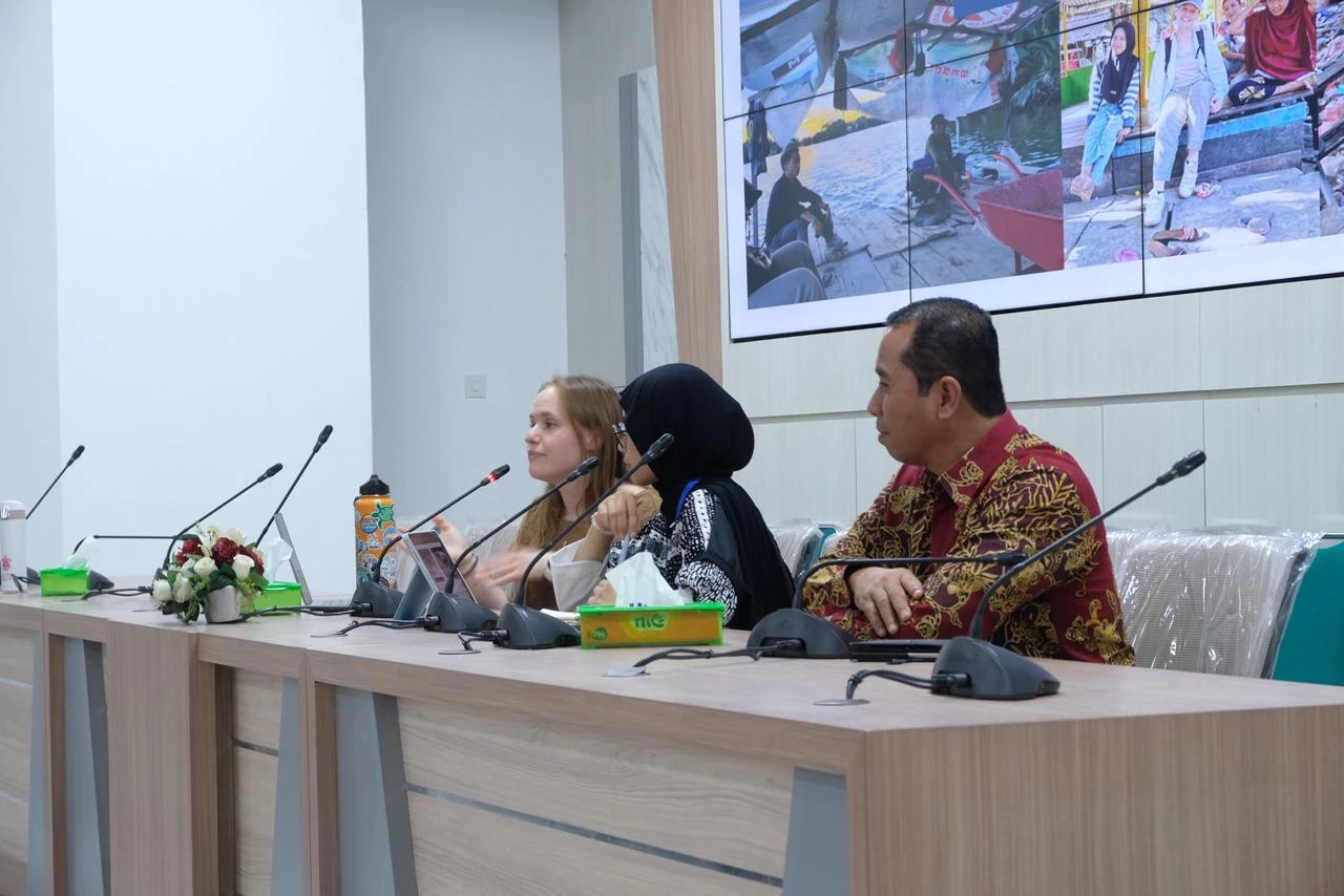Morgan Tarpenning (kiri) sedang menjelaskan bagaimana teknologi drone membantu mengidentifikasi ban bekas yang menjadi sarang nyamuk, sebuah temuan penting dari penelitiannya di Makassar. Sesi ini menjadi bagian dari PKKMB FKM Unhas, yang bertujuan membekali mahasiswa baru dengan wawasan inovatif dan relevan tentang isu kesehatan masyarakat. Kredit: FKM UNHAS.